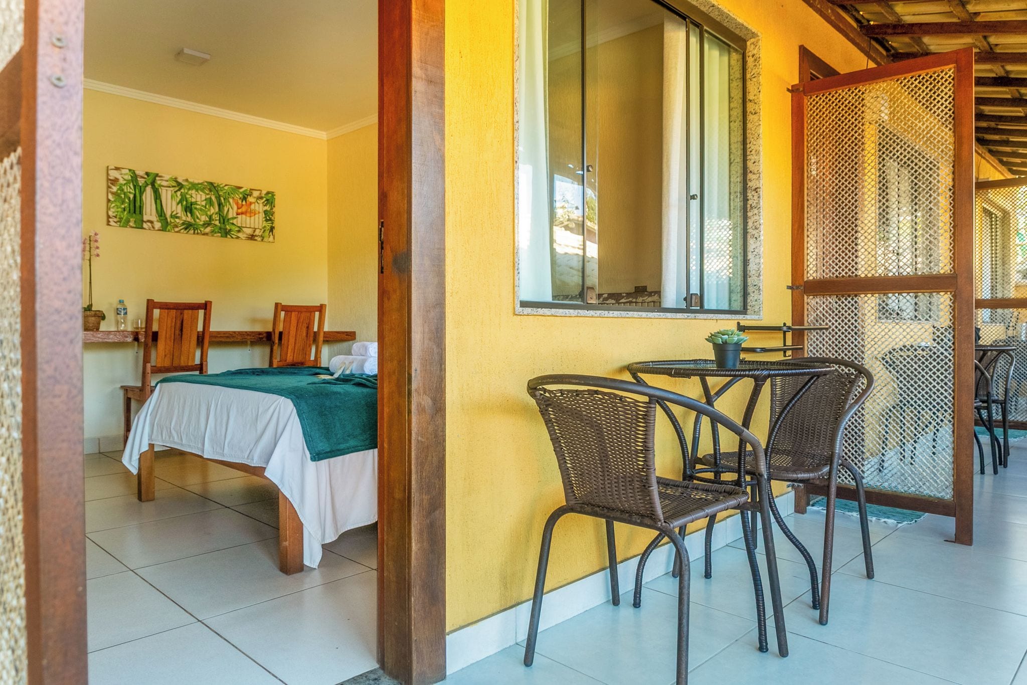 A room with a bed, two chairs, a table, and a window.