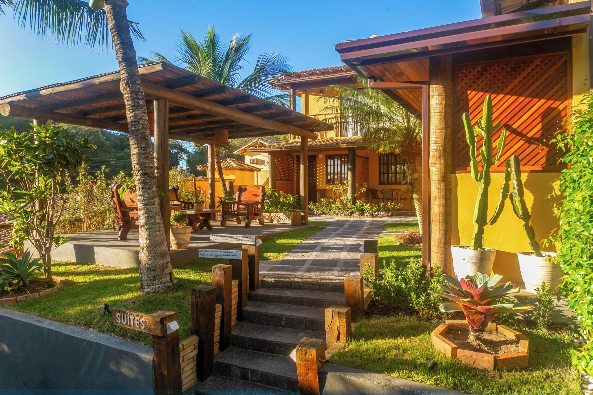 Un resort con una zona de estar al aire libre techada, una escalera que lleva a un edificio y un cartel que indica 'SUITES'.