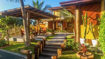 Un resort con una zona de estar al aire libre techada, una escalera que lleva a un edificio y un cartel que indica 'SUITES'.