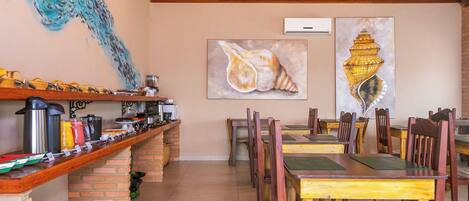 Ein Restaurant mit einer langen Theke, mehreren Sitzplätzen und Kunstwerken an den Wänden.