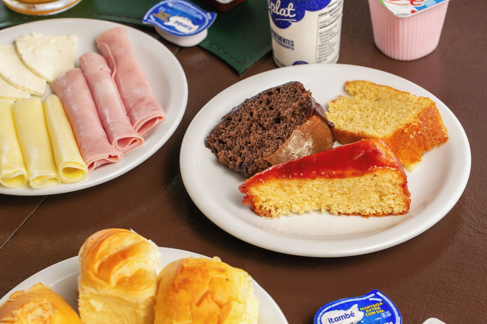 Une table dressée avec des assiettes remplies de nourriture, notamment des crêpes, une part de gâteau et des petits pains.