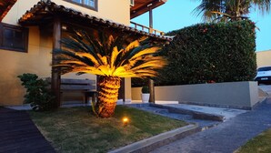 A well-lit palm tree in a landscaped area with a building in the background. - Pousada Búzios Garden (Búzios)