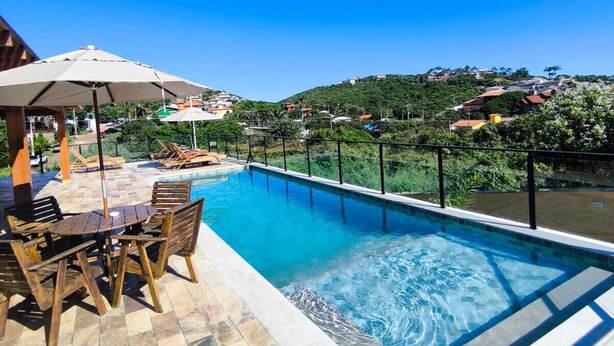 A swimming pool with a tiled deck, outdoor furniture, and umbrellas. - Pousada Búzios Garden (Búzios)