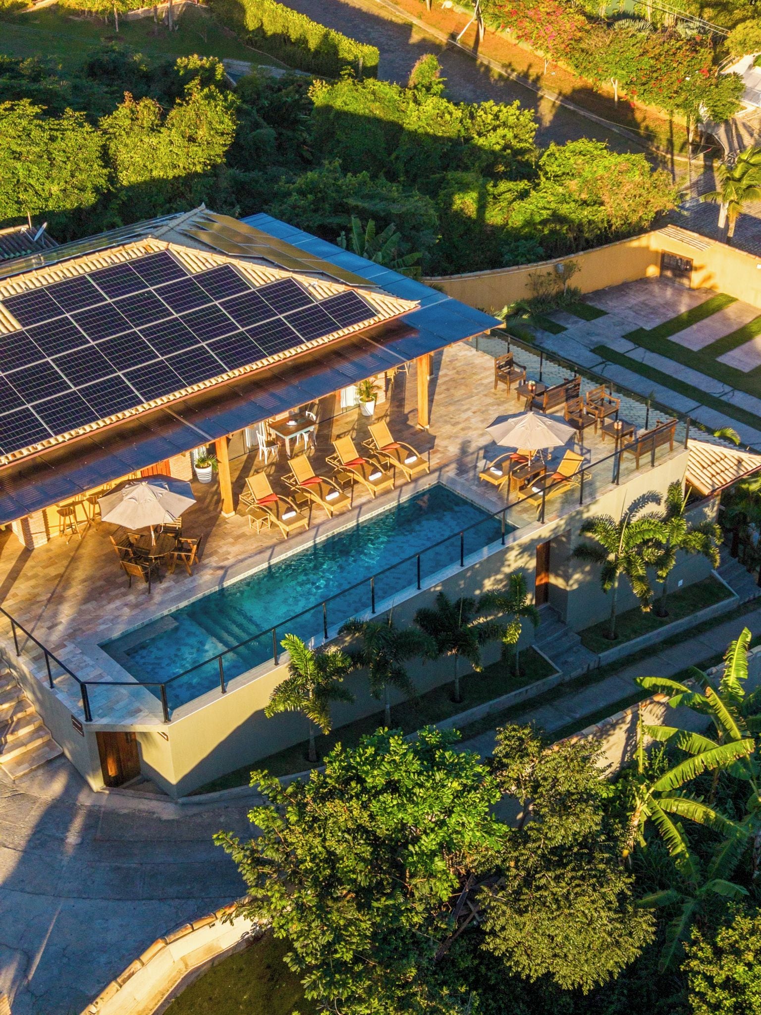Área de piscina no terraço com painéis solares, espreguiçadeiras e uma piscina.