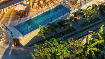 Área de piscina no terraço com painéis solares, espreguiçadeiras e uma piscina.