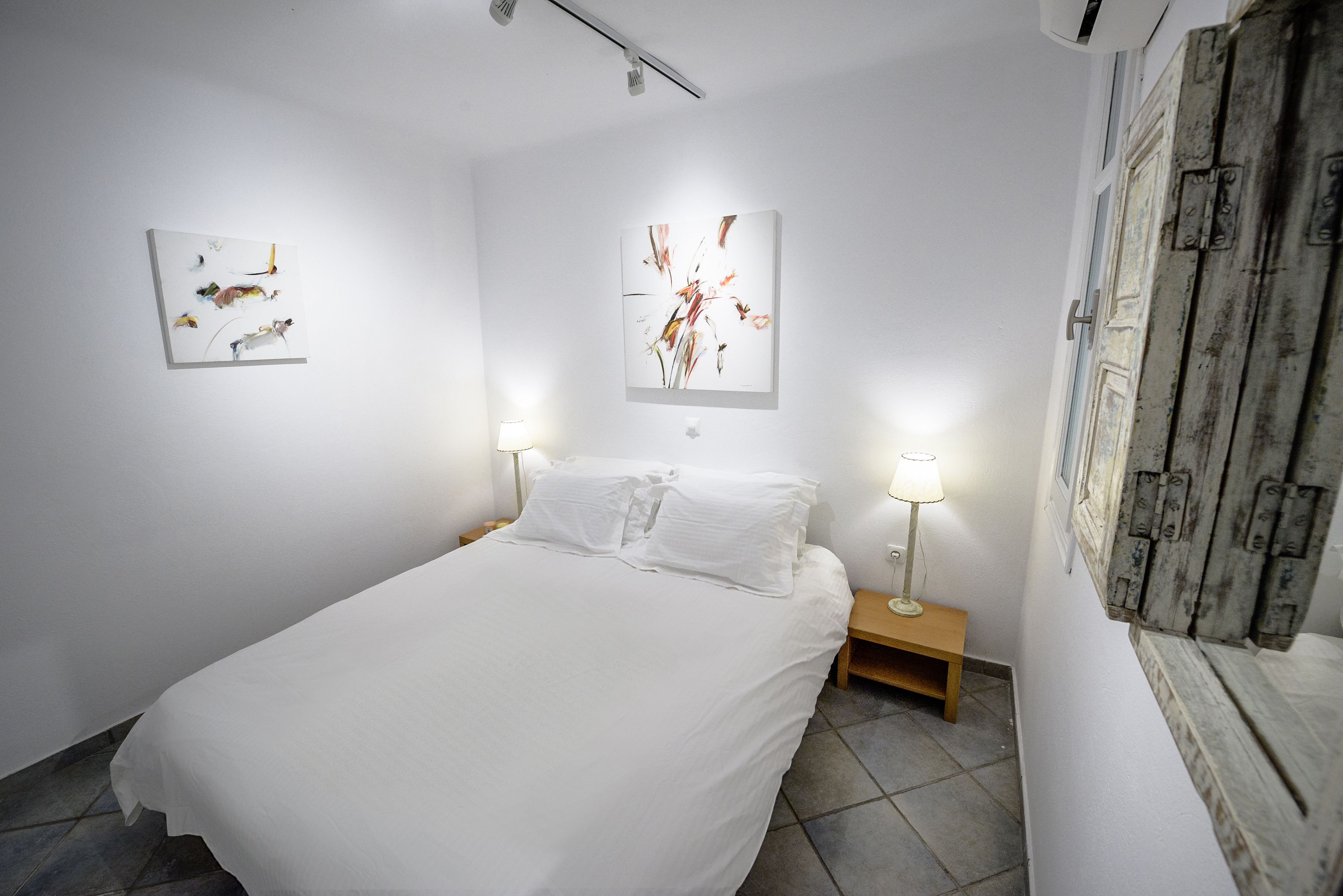 A bedroom with a bed, two bedside tables, and two wall-mounted lamps.
