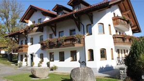 Un edificio grande y blanco con varios balcones, vigas de madera y jardineras.