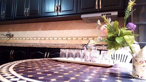 A kitchen with dark cabinets, a patterned backsplash, and a round table with a decorative vase. - Villa Annakhil Families And Couples (Marrakech)