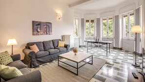 A living room with a grey sofa, a coffee table, and a painting on the wall. - AwesHome - Sea Sensation Apartment (La Spezia)