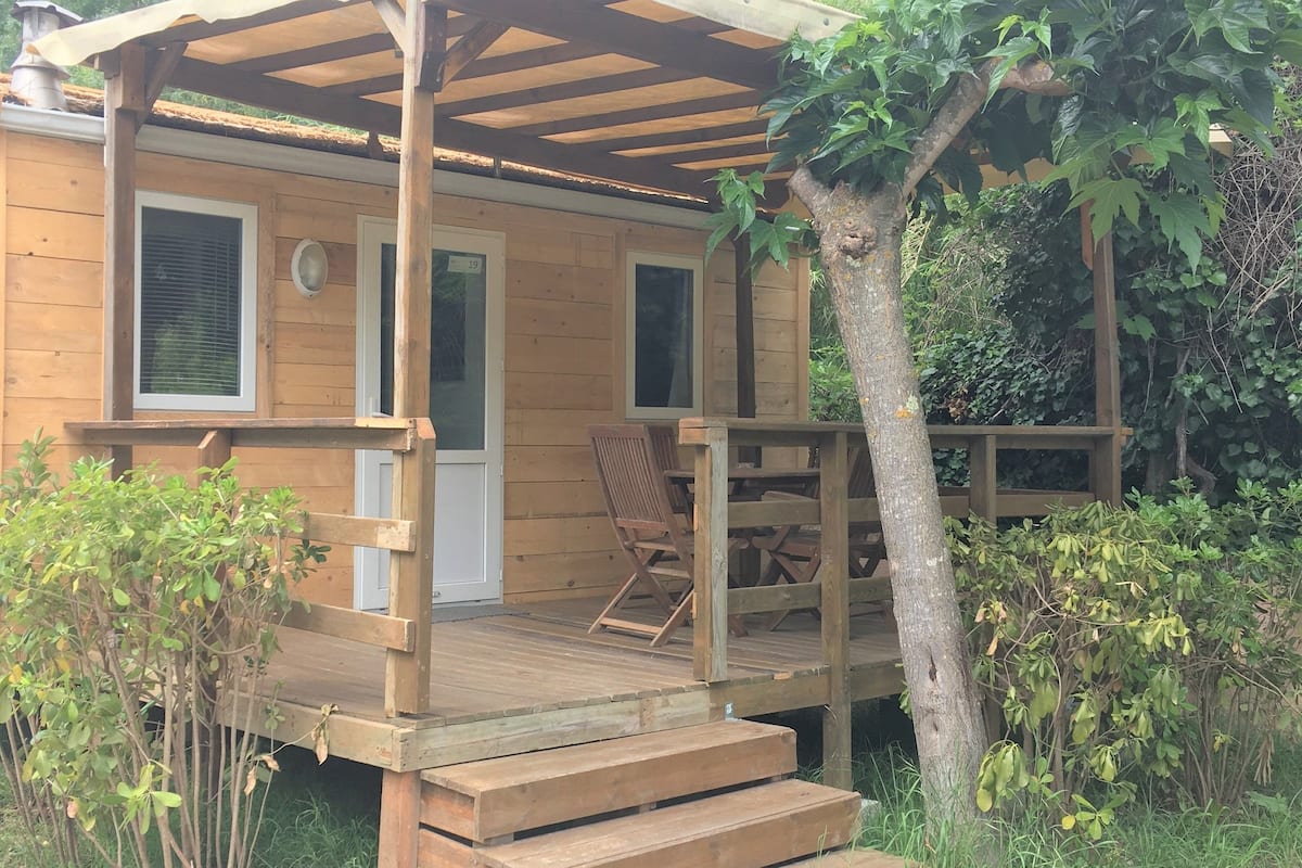 Una cabaña de madera con un porche, una puerta y una ventana.