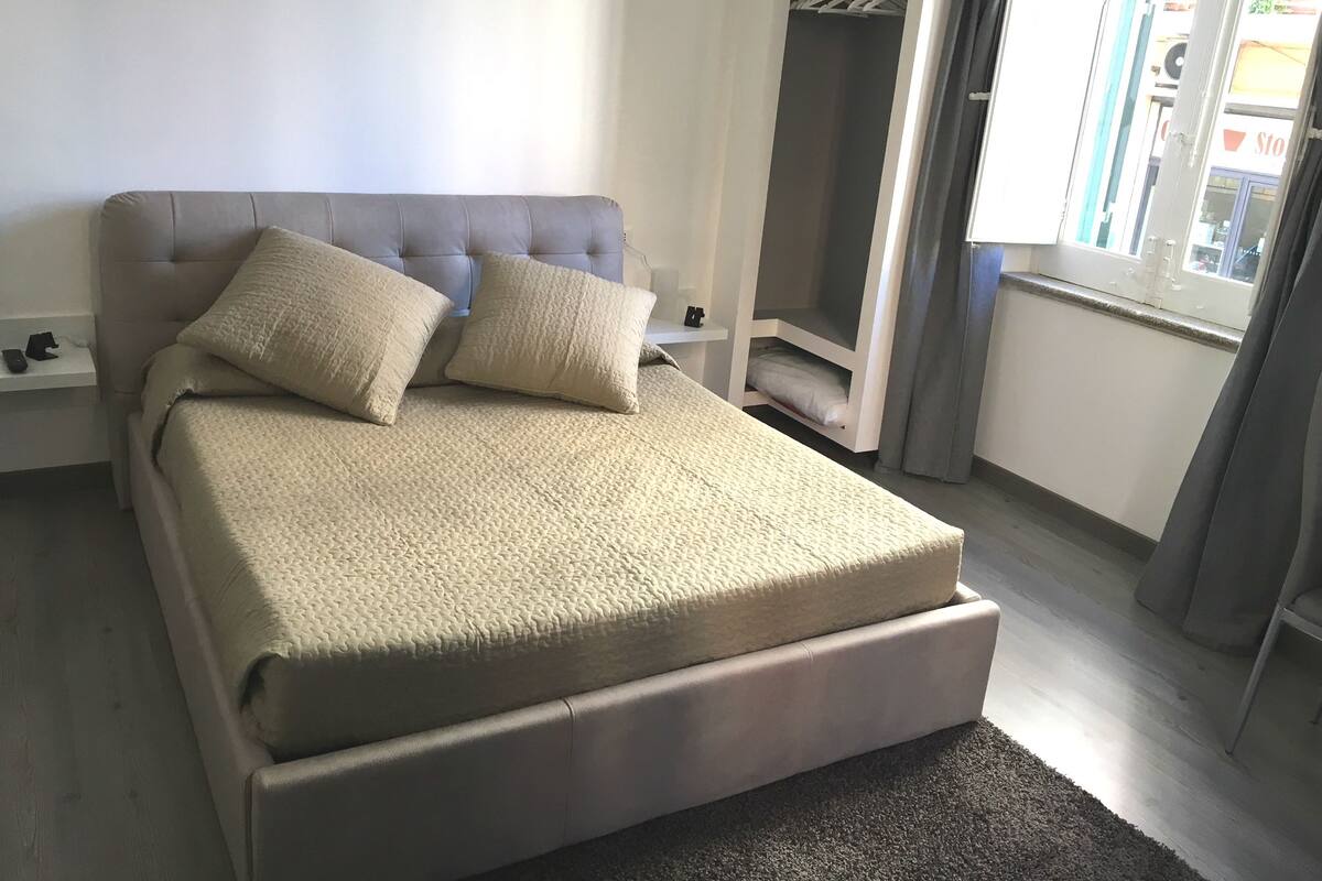 A bedroom with a large bed, a wardrobe, and a window with curtains.
