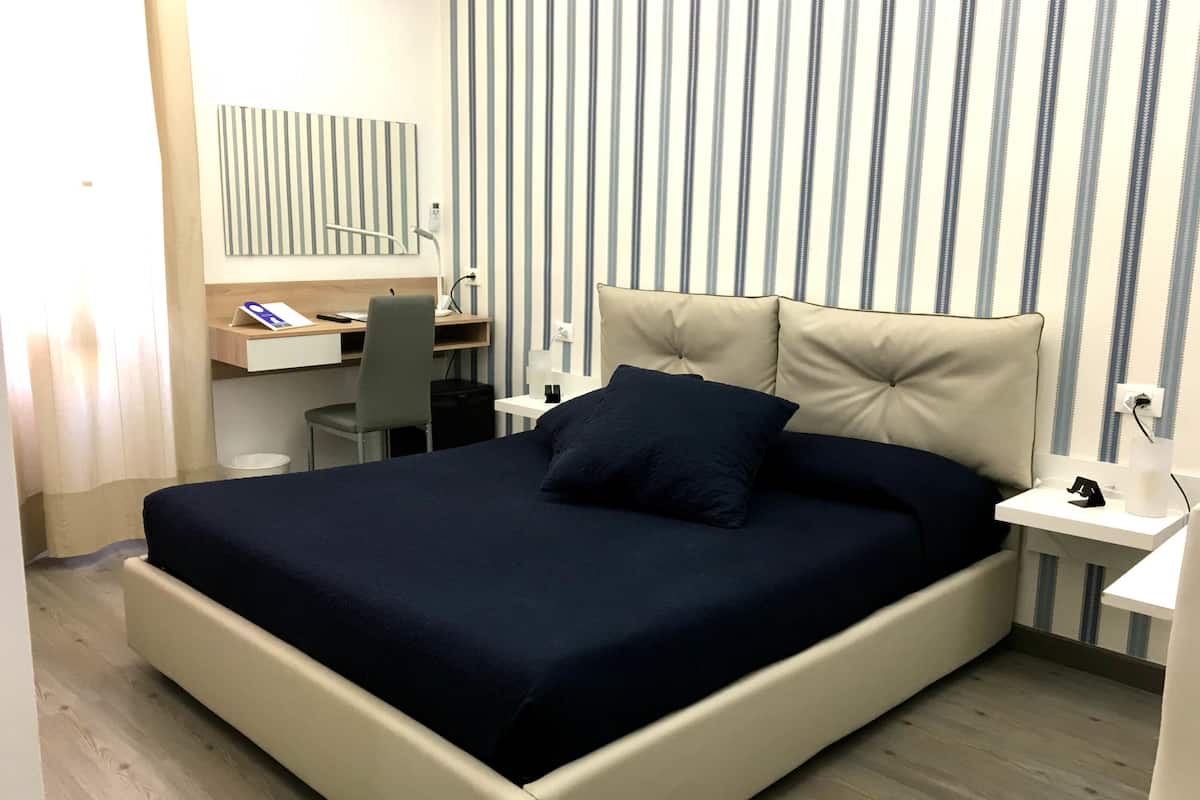 A neatly arranged hotel room with a bed, a desk, and a chair.
