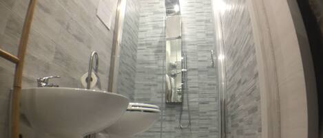 A bathroom with a glass-enclosed shower, a sink, and a toilet.