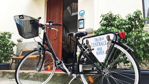 Una bicicleta estacionada frente a un edificio con un letrero que dice "B&B CENTRALE" y números de contacto.