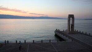 Un paseo marítimo con un monumento de piedra y un mar tranquilo.