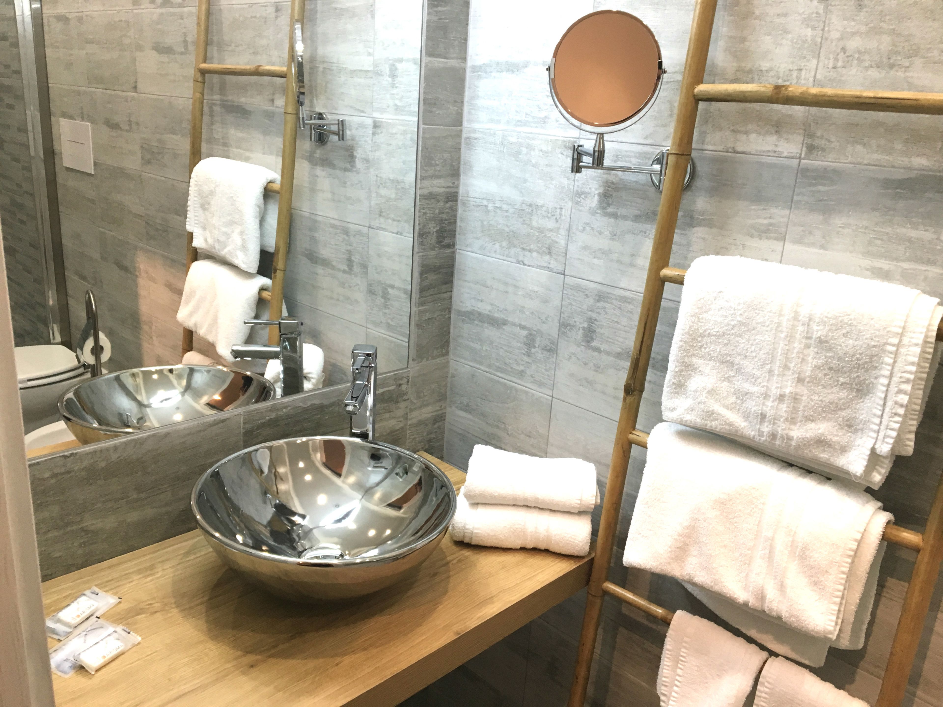 A modern bathroom with a large mirror, two sinks, and a towel rack.