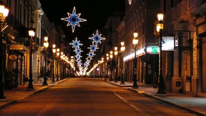 Una calle flanqueada por edificios decorados con luces en forma de estrella.