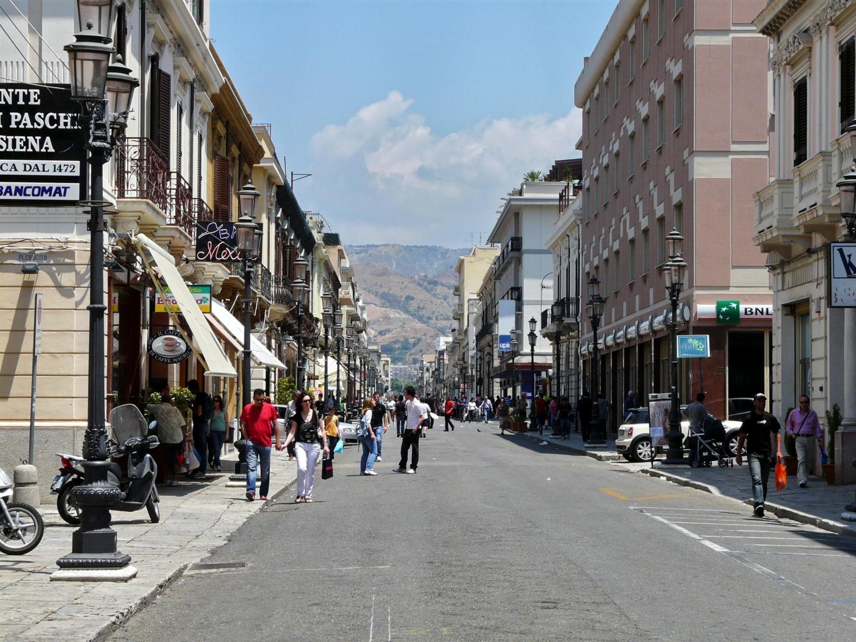 A street lined with buildings, some with signs indicating businesses.