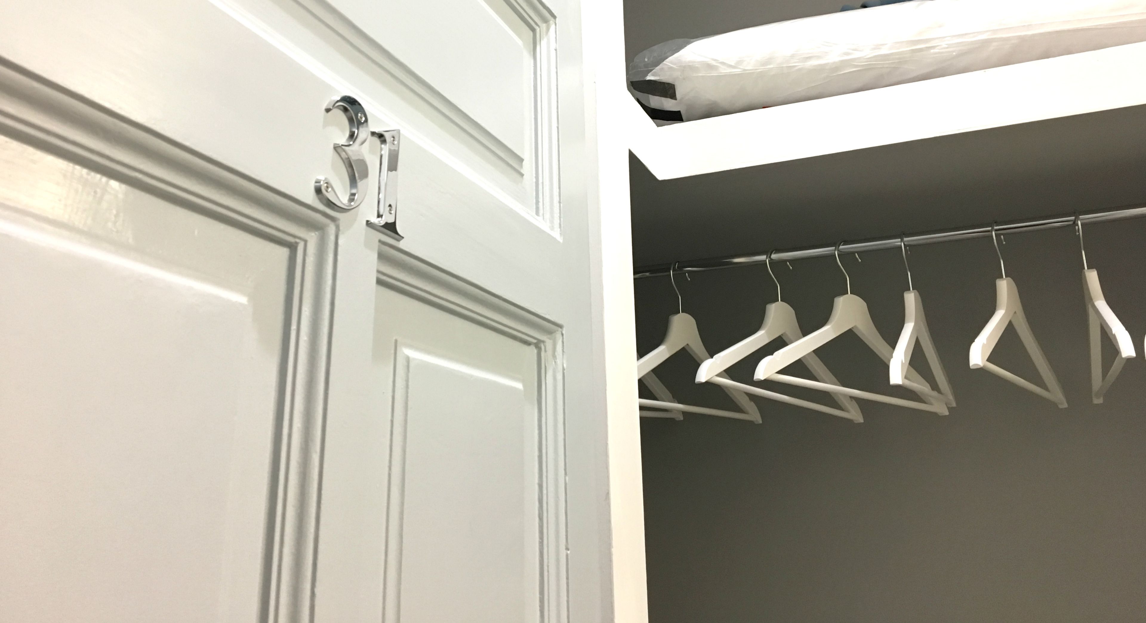 A white door with a silver handle and a closet with white hangers.