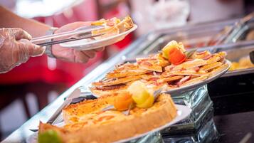 Un buffet proposant divers plats, notamment des pizzas et un gâteau.
