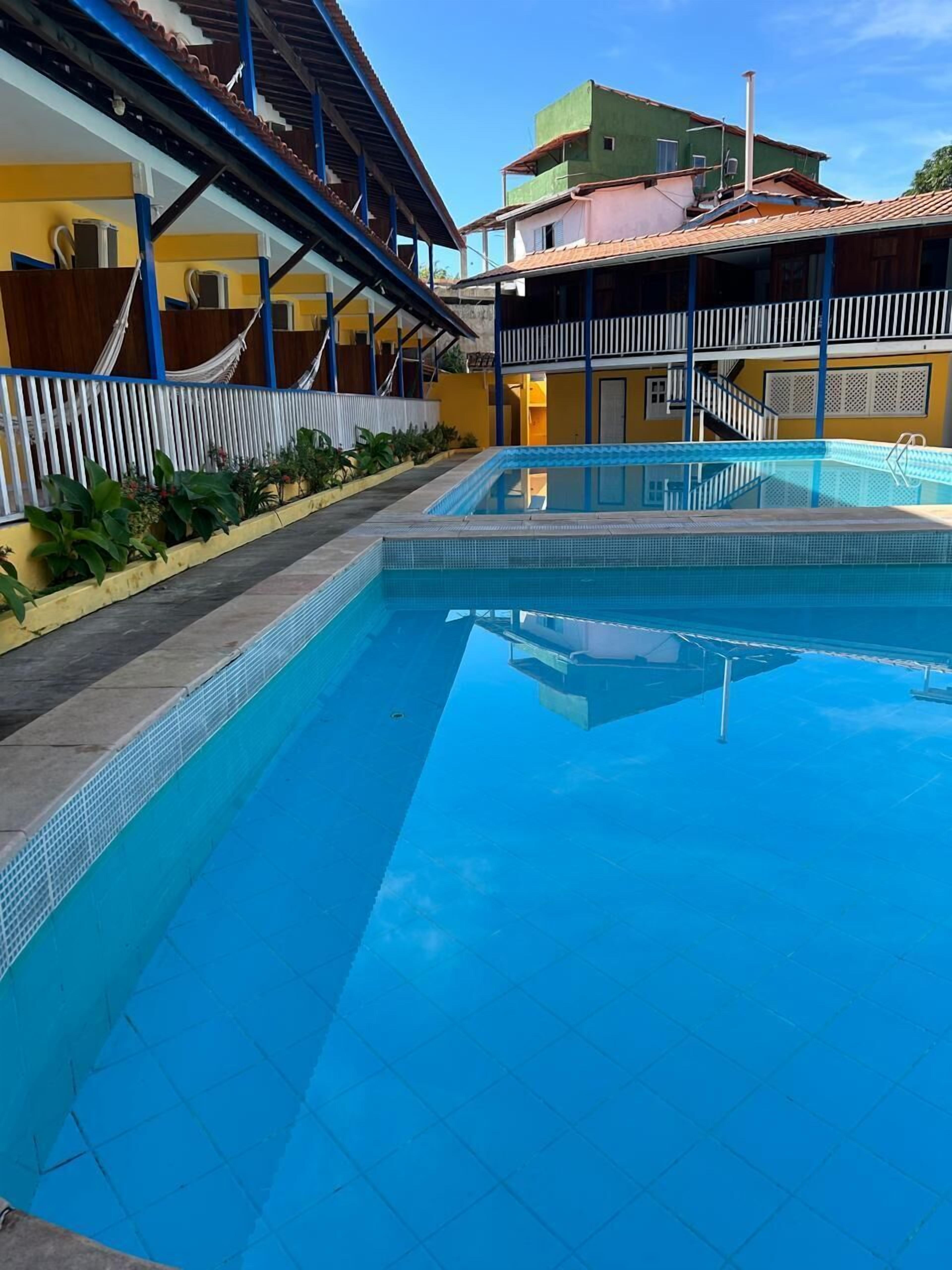 Una piscina con solarium de baldosas, rodeada por edificios con balcones y barandillas.