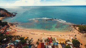 Una playa con aguas cristalinas, una orilla arenosa y algunas sombrillas y sillas de playa.