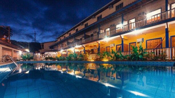 Un hotel con piscina, varios balcones e iluminación exterior.