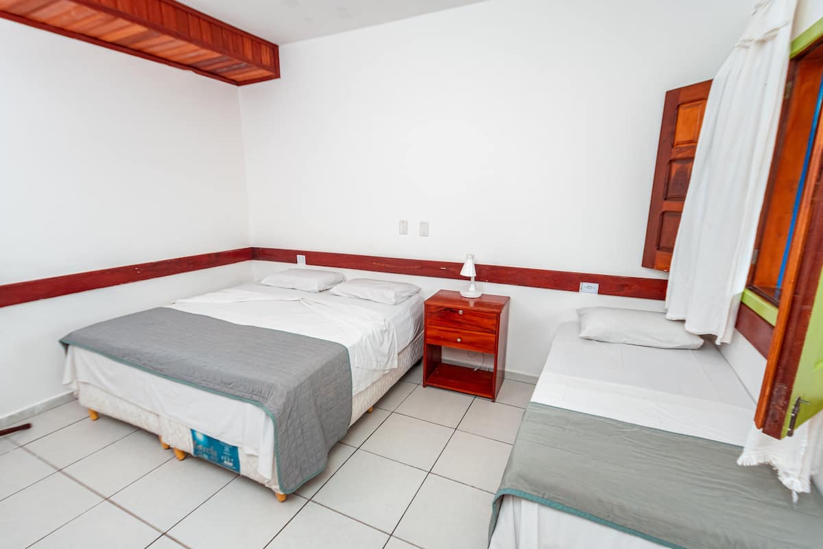 A bedroom with two beds, a wooden nightstand, and a small table.