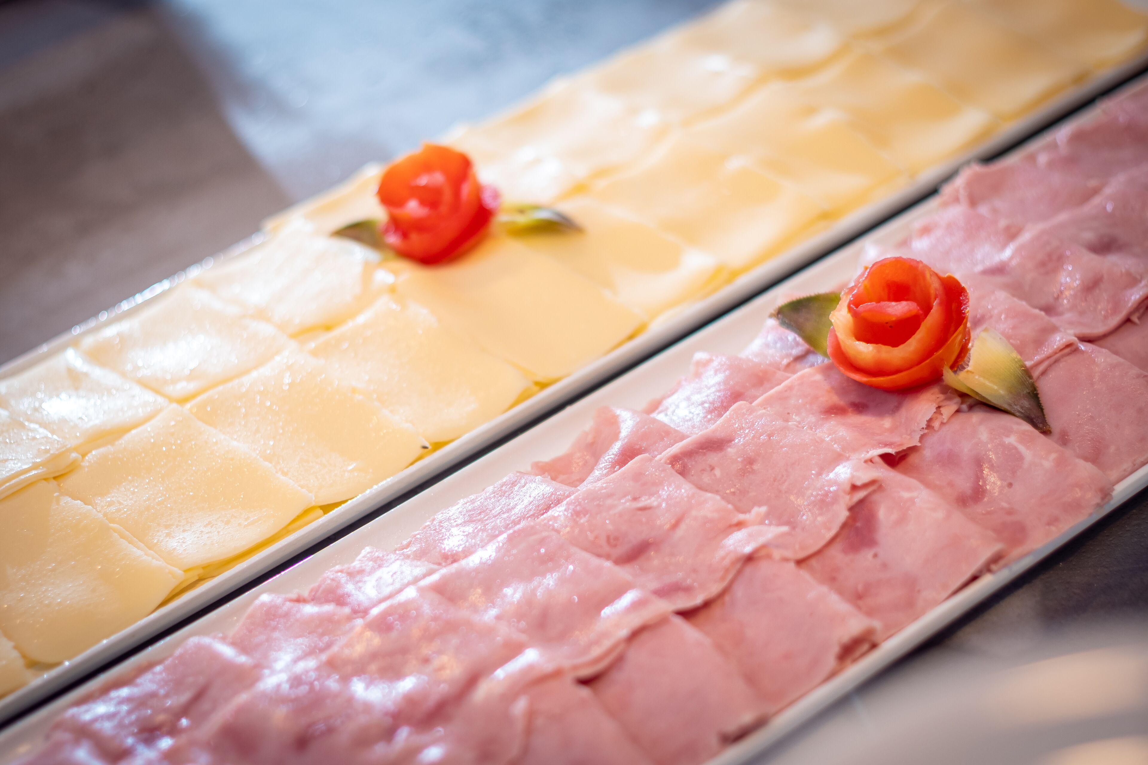 A tray of sliced cheese and ham with decorative roses.