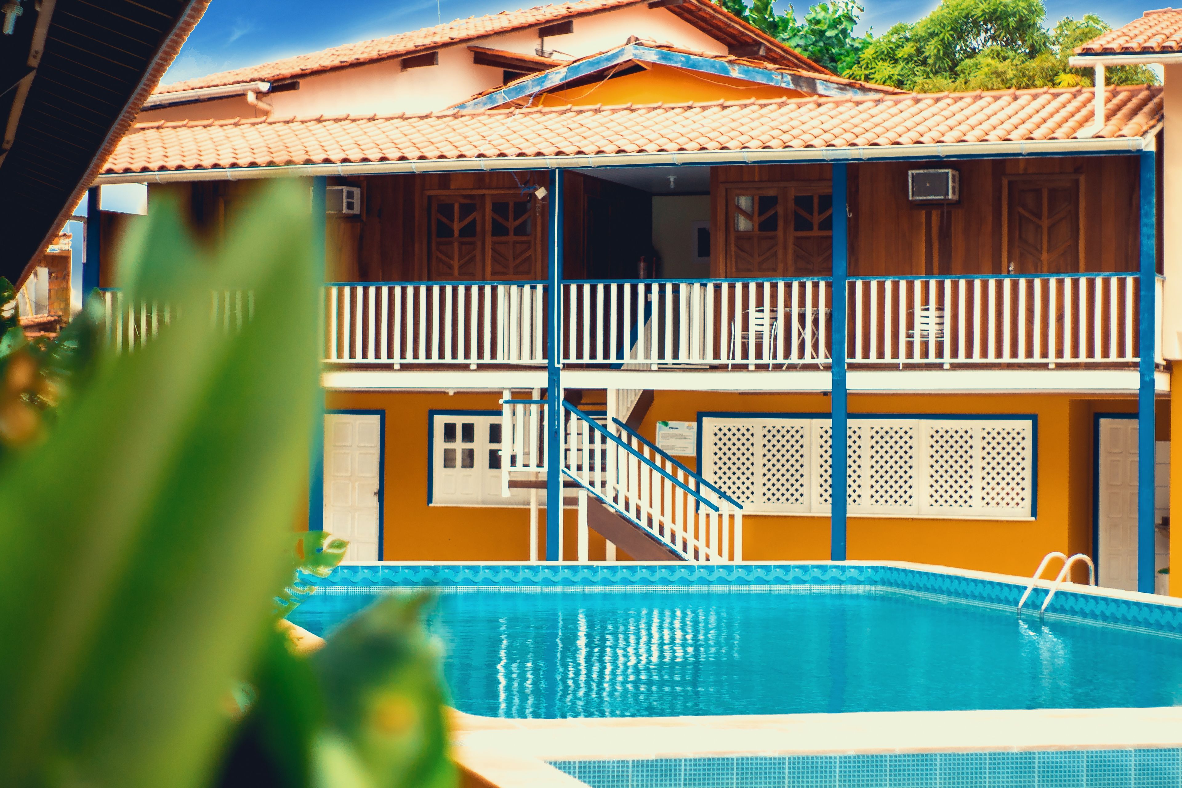 A two-story building with a swimming pool, balconies, and a staircase leading to the upper floor.