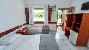 Habitación de hotel con dos camas, una mesita pequeña, una silla, un armario de madera y un televisor.