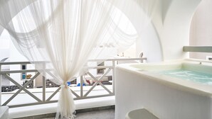 Un balcon avec une baignoire blanche et des rideaux transparents.