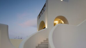 Un escalier moderne au design architectural unique, menant à un bâtiment doté de fenêtres en arc de cercle.