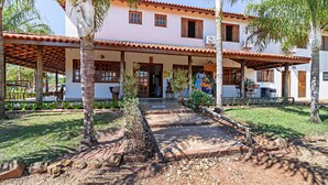 A two-story building with a tiled roof and a covered patio area. - Pousada Pé na Terra (Brotas)