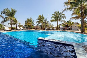 Una piscina al aire libre, sillones reclinables de piscina