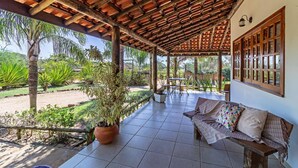 A covered patio with a wooden ceiling, a sofa with cushions, and a potted plant. - Pousada Pé na Terra (Brotas)