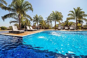 Una piscina al aire libre, sillones reclinables de piscina