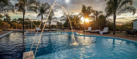 Una piscina al aire libre, sillones reclinables de piscina