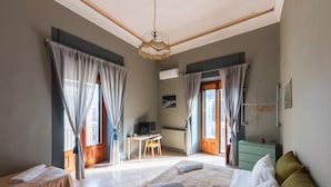 A hotel room with two beds, a desk, and a television. - Terrazza Santa Chiara (Catania)