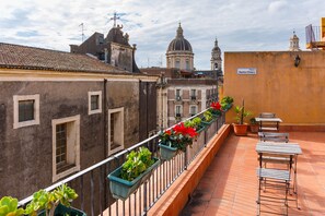 Una terraza con plantas en macetas y mobiliario de exterior.