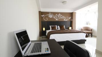 Una habitación de hotel con una cama, un escritorio con una computadora portátil, una silla y una decoración de pared.
