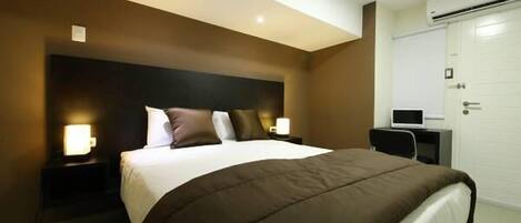 Una habitación de hotel moderna con una cama grande, lámparas de noche, un escritorio y un armario.
