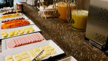 Un bufé con diversas opciones de comida, incluyendo frutas, quesos y carnes.