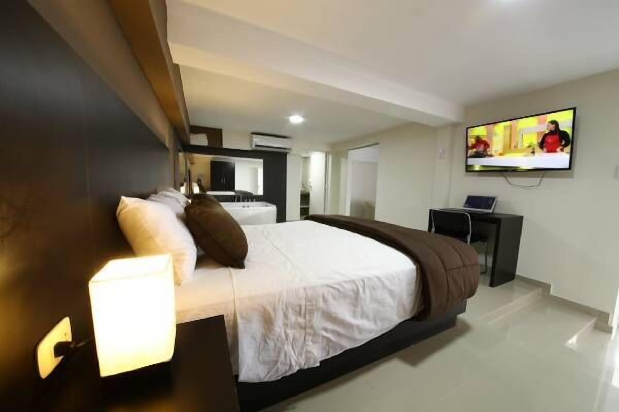 Habitación de hotel moderna con una cama grande, un televisor de pantalla plana en la pared y un escritorio con una silla.
