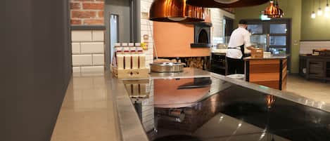 A modern kitchen with copper pendant lights, a brick wall, and a chef preparing food.