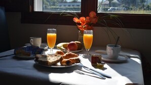 Una mesa de desayuno con tostadas, croissants, un plato de fruta y dos vasos de zumo de naranja.