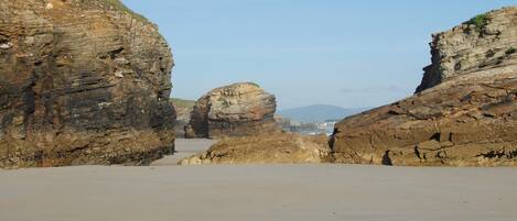 Un paisaje costero con formaciones rocosas destacadas y una playa de arena.