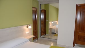 Una habitación de hotel con cama, mesita de noche y espejo.