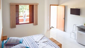 Una camera da letto con un letto, una finestra, una porta, una TV e una scrivania.