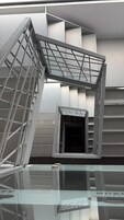 Una estructura arquitectónica moderna con una escalera de cristal y barandillas de metal.